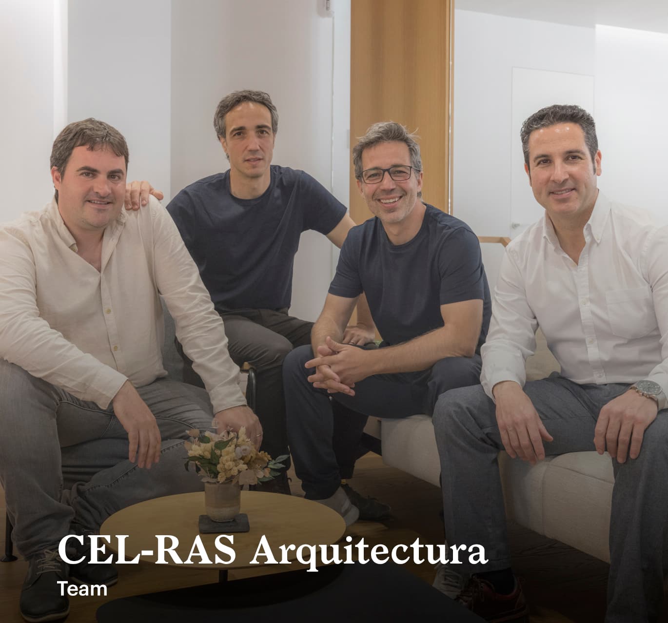 Four men sitting together in a modern office space, smiling at the camera. Text reads "CEL-RAS Arquitectura Team. They are architects: Juan Miguel Gil, José Luis Doménech, and Victor Masip.
