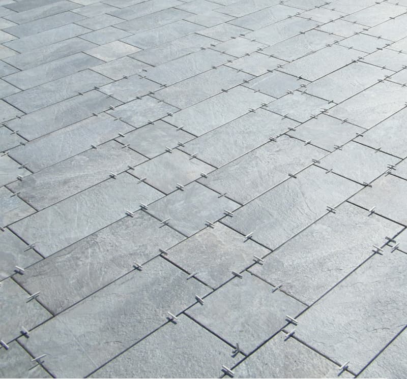 Close-up of a gray rectangular stone tile floor with visible grout lines, arranged in an interlocking pattern.